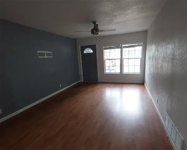 an empty room with wooden floor and windows