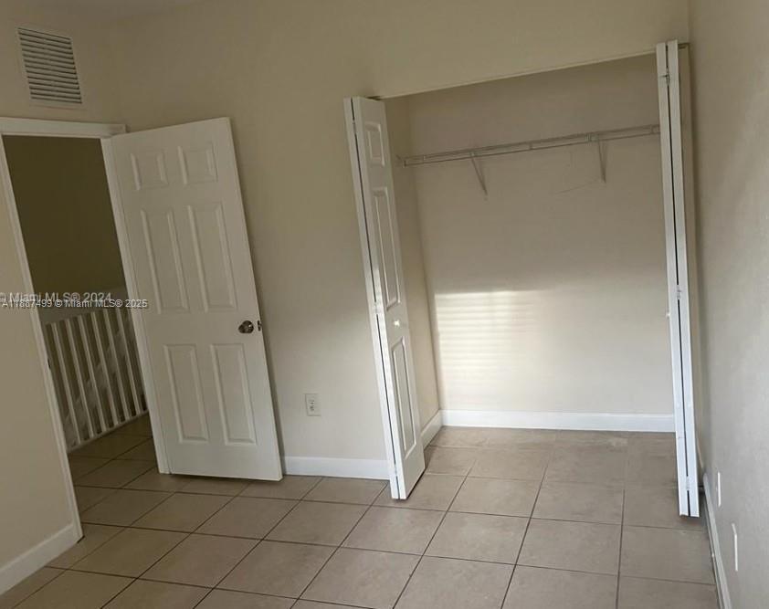 205 Southeast 29th Terrace, Unit 5 Homestead, FL 33033 - Photo 10 of 17 a view of an empty room with wooden floor and a window