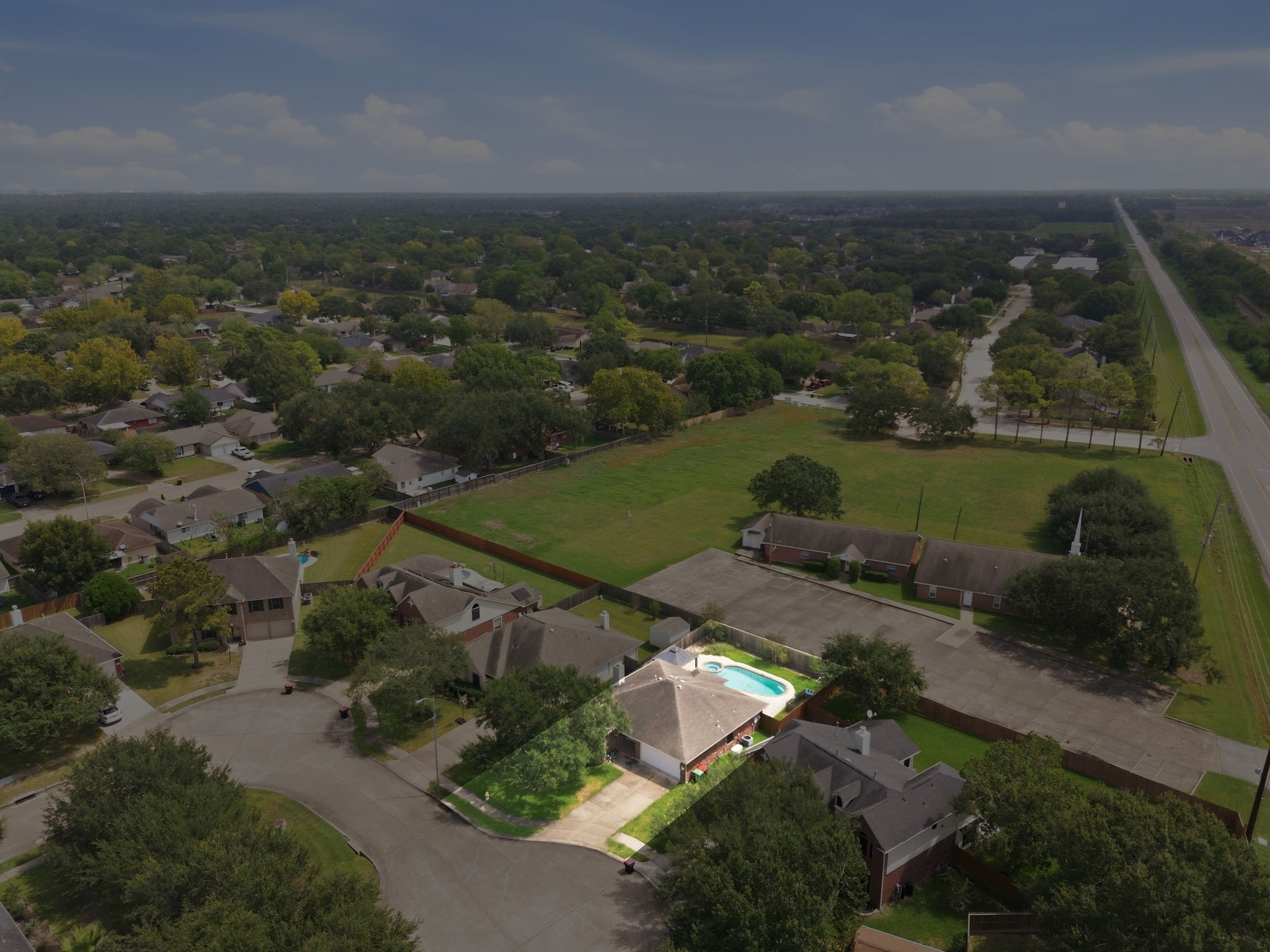 6911 River Road Richmond, TX 77469 - Photo 35 of 36 Positioned on an advantageous cul-de-sac lot, this elevated perspective showcases the property's prime footprint bordering expansive open land with no rear residential neighbors. The highlighted single-story residence features an extended driveway, leafy front yard shade, and an enclosed backyard centered around an in-ground swimming pool, presenting solid long-term investment potential.