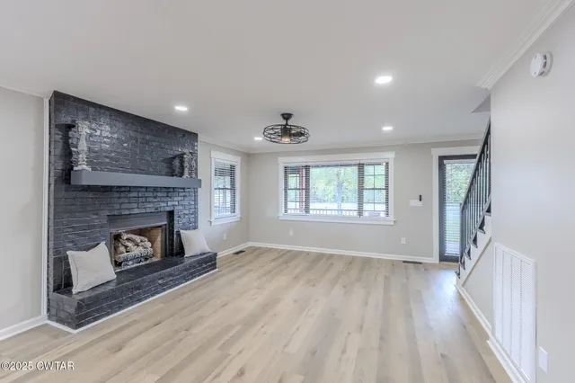 a view of an empty room with wooden floor fireplace and a window