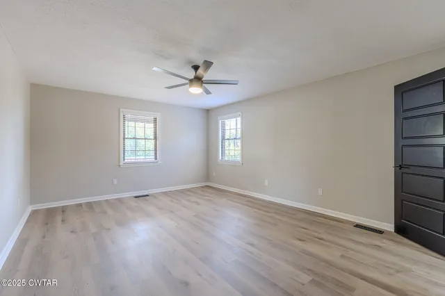 a view of an empty room with a window and wooden floor
