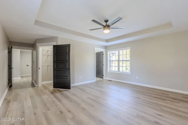 a view of an empty room with wooden floor and window