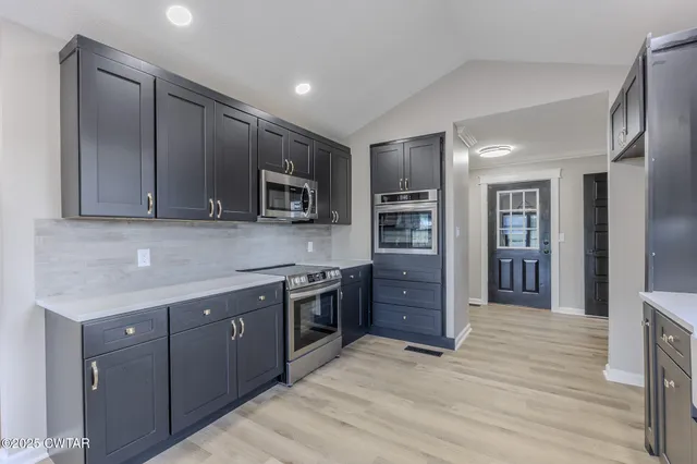 a kitchen with stainless steel appliances granite countertop a refrigerator and a stove top oven
