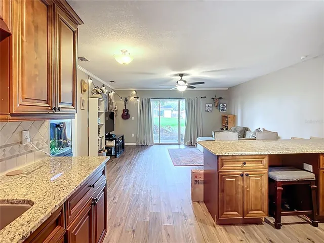 a view of a kitchen with kitchen island granite countertop wooden floor and a refrigerator