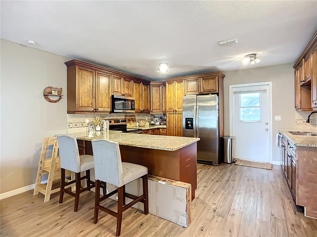 1304 Alfred Street, Unit B Brandon, FL 33510 - Photo 10 of 26 a kitchen with stainless steel appliances granite countertop wooden floor a refrigerator a sink dishwasher and a stove with wooden floor