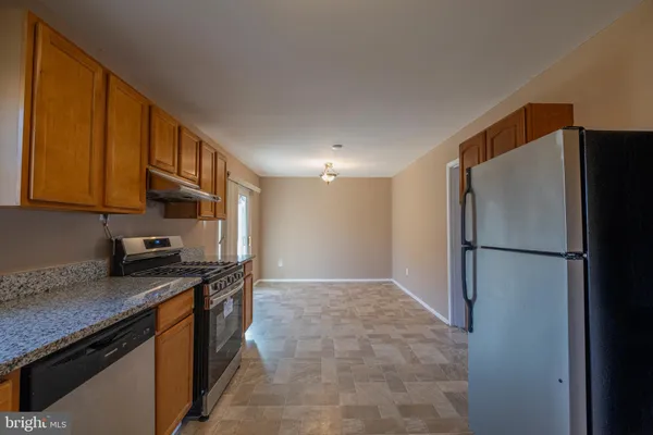 a kitchen with stainless steel appliances granite countertop a refrigerator a stove and a sink