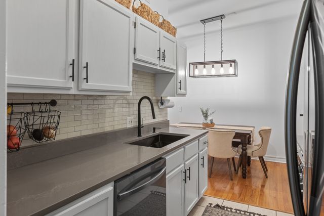 a kitchen with stainless steel appliances a sink a stove and white cabinets