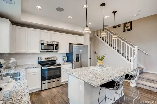 a kitchen with stainless steel appliances granite countertop a sink a stove and a wooden floors