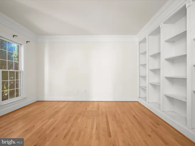 a view of an empty room with window and wooden floor