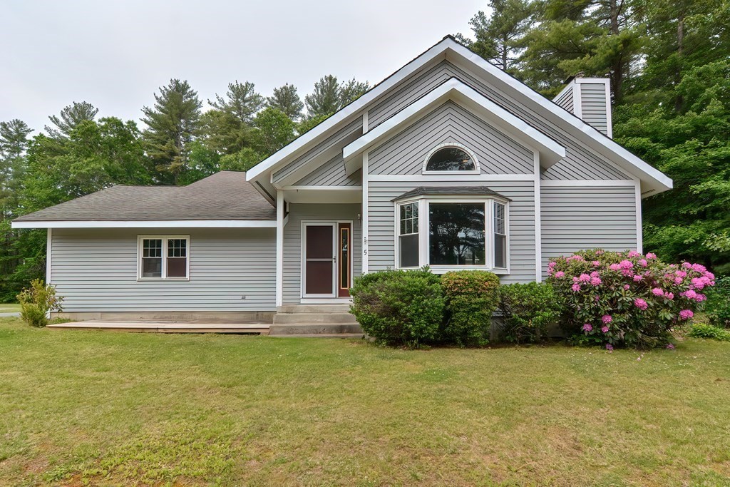 a front view of house with yard and trees in the background