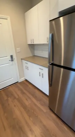 a view of a refrigerator in kitchen and white cabinets