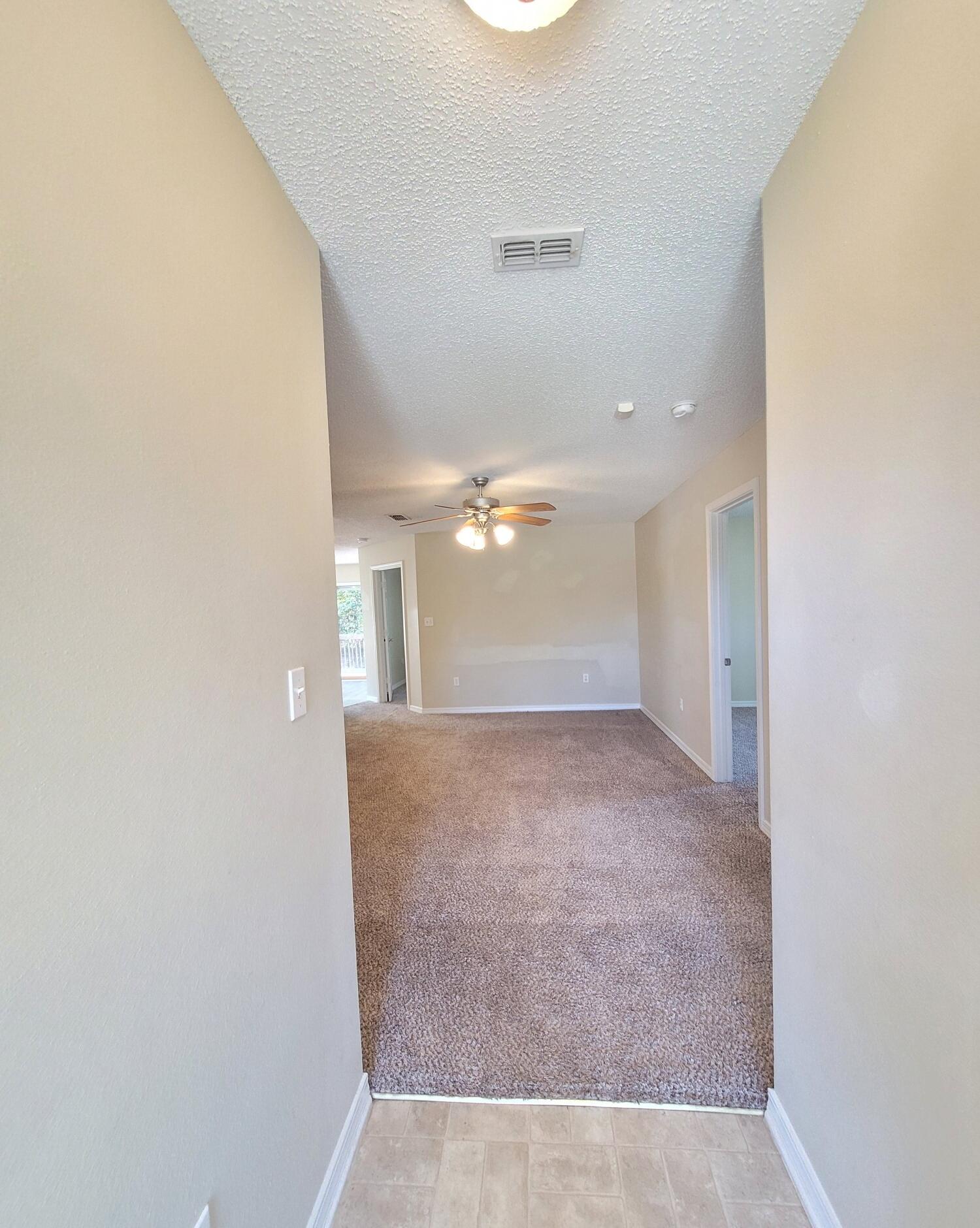 268 Limestone Circle Crestview, FL 32539 - Photo 4 of 23 an empty room with a ceiling fan and kitchen view