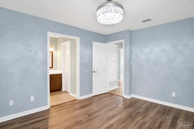 an empty room with wooden floor and a hallway