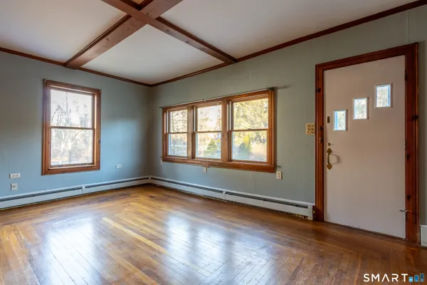 an empty room with wooden floor fireplace and windows