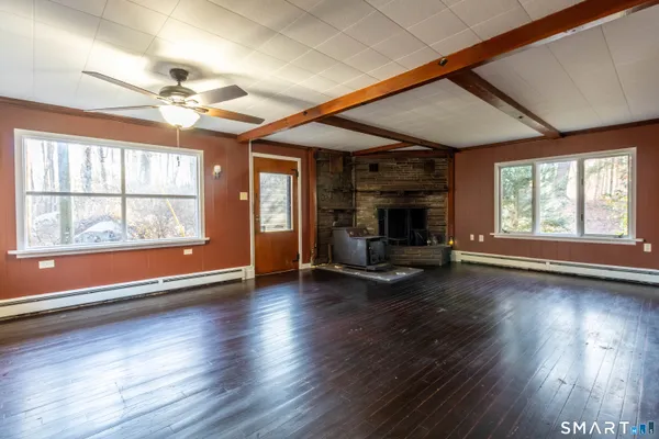a view of an empty room with wooden floor and a window