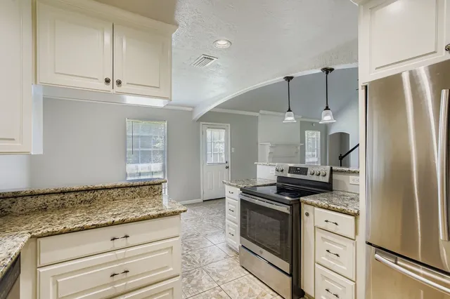 a kitchen with granite countertop a refrigerator and a stove top oven