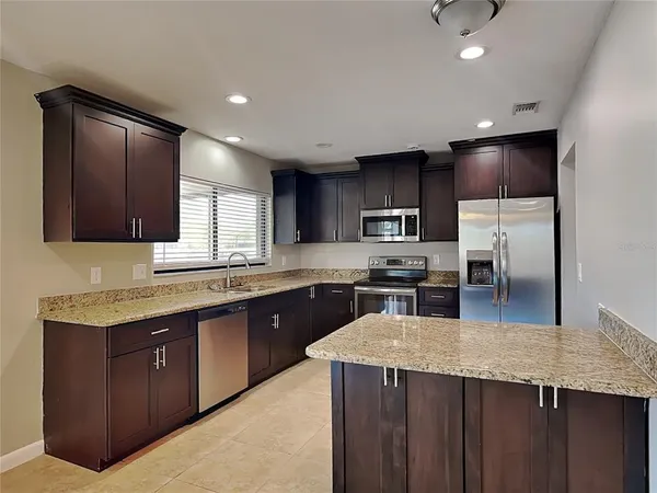 a kitchen with granite countertop a sink counter top space stainless steel appliances and cabinets