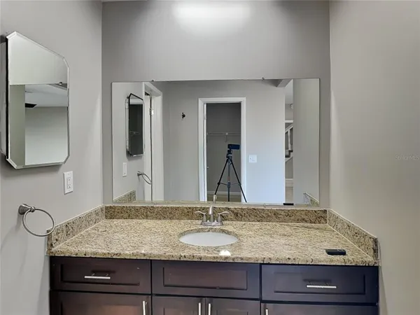 a bathroom with a granite countertop sink and a mirror