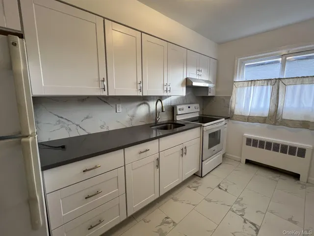 a kitchen with granite countertop white cabinets and stainless steel appliances
