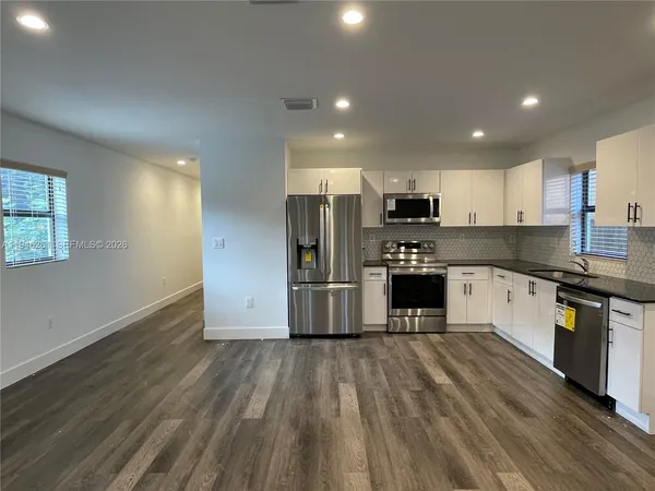 a kitchen with granite countertop a refrigerator and a stove top oven