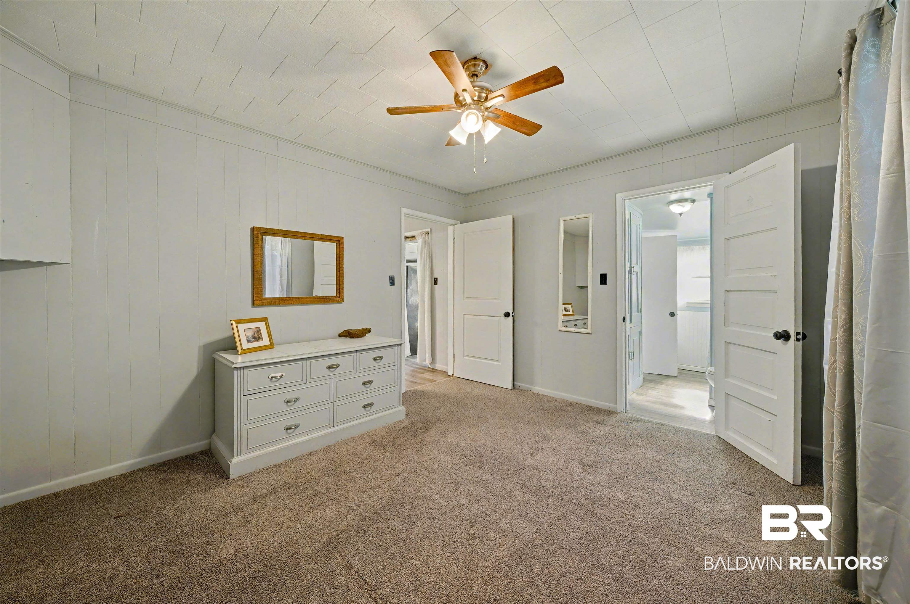 209 West Magnolia Avenue Foley, AL 36535 - Photo 16 of 23 Unfurnished bedroom featuring light colored carpet, a ceiling fan, and wooden walls