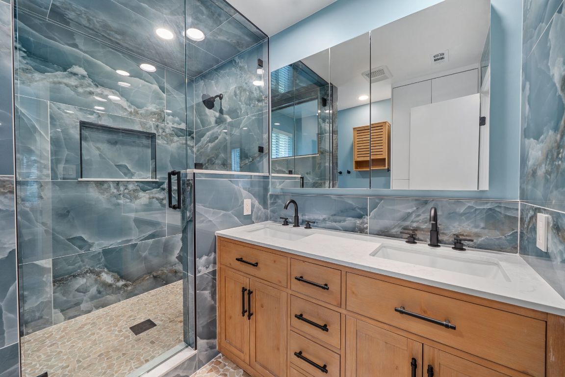 2175 Park Road New Braunfels, TX 78132 - Photo 19 of 39 Bathroom featuring double vanity, a marble finish shower, tile walls, and tasteful backsplash