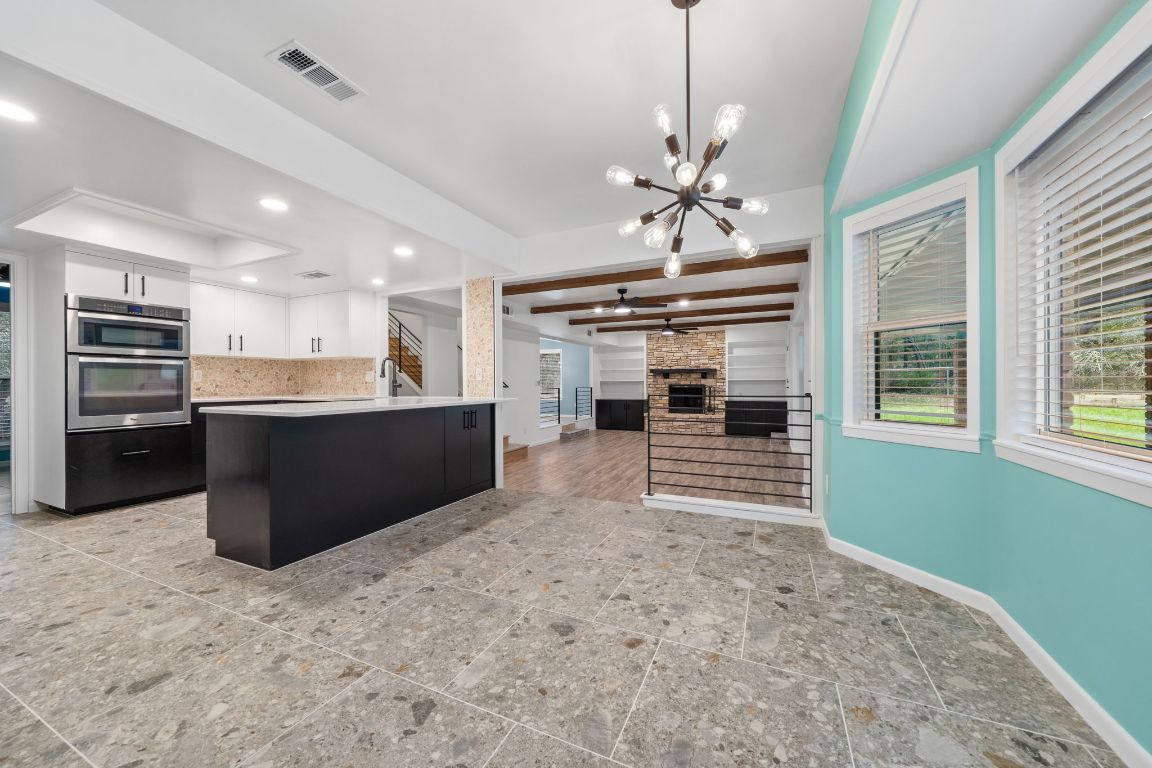 2175 Park Road New Braunfels, TX 78132 - Photo 37 of 39 Kitchen featuring white cabinetry, dark cabinetry, open floor plan, a fireplace, and a chandelier