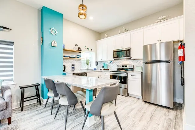 a kitchen with a refrigerator a stove top oven a sink dishwasher and white cabinets with wooden floor