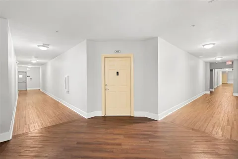a view of a big room with wooden floor and windows