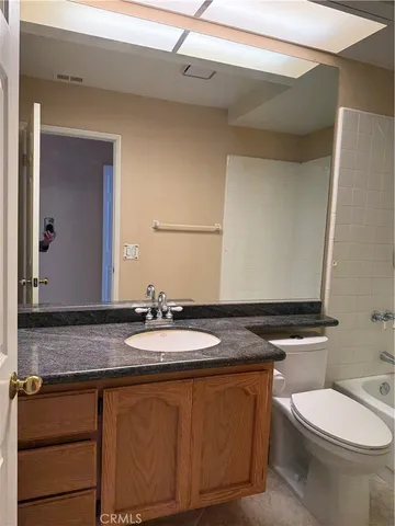 a bathroom with a granite countertop toilet sink and mirror