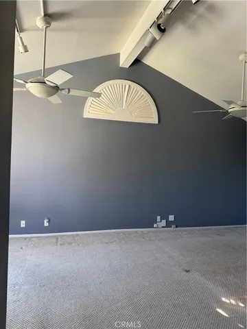 an empty room with a chandelier fan and wooden floor