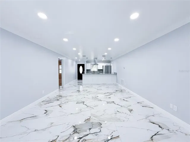 a view of a kitchen with kitchen island a sink wooden floor and a refrigerator