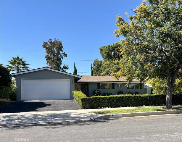 a front view of a house with a garden and trees
