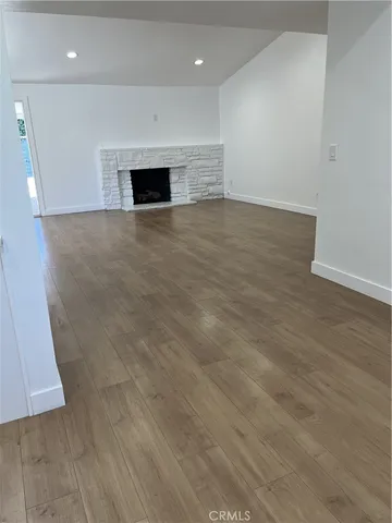 an empty room with wooden floor and fireplace