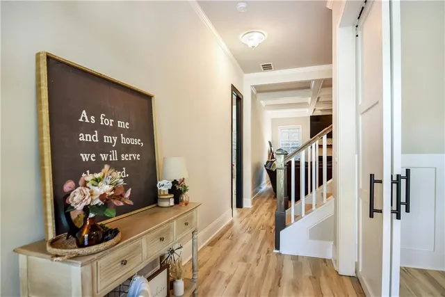 a view of a hallway to a livingroom with wooden floor and furniture