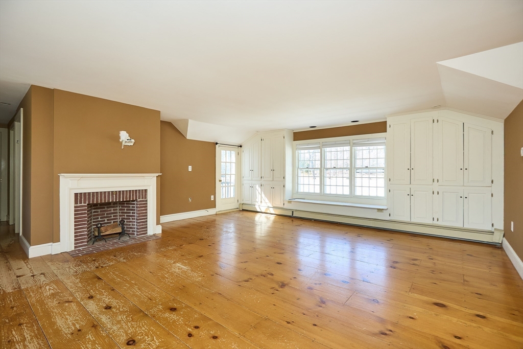 685 Highland Street Marshfield, MA 02050 - Photo 23 of 38 an empty room with fireplace wooden floor and windows