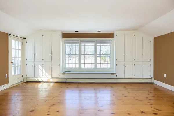 an empty room with wooden floor and windows
