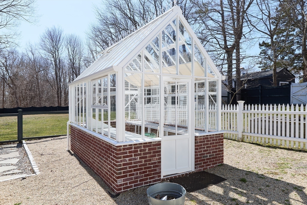 685 Highland Street Marshfield, MA 02050 - Photo 32 of 38 a view of a brick house with wooden fence and a bench