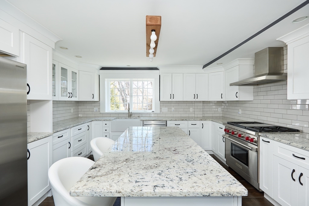 685 Highland Street Marshfield, MA 02050 - Photo 7 of 38 a large kitchen with granite countertop a stove a sink a window and white cabinets