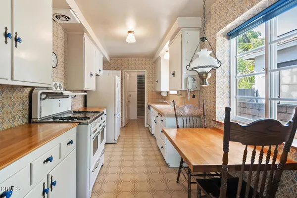 a kitchen with stainless steel appliances granite countertop a stove a refrigerator a oven with white cabinets and wooden floor