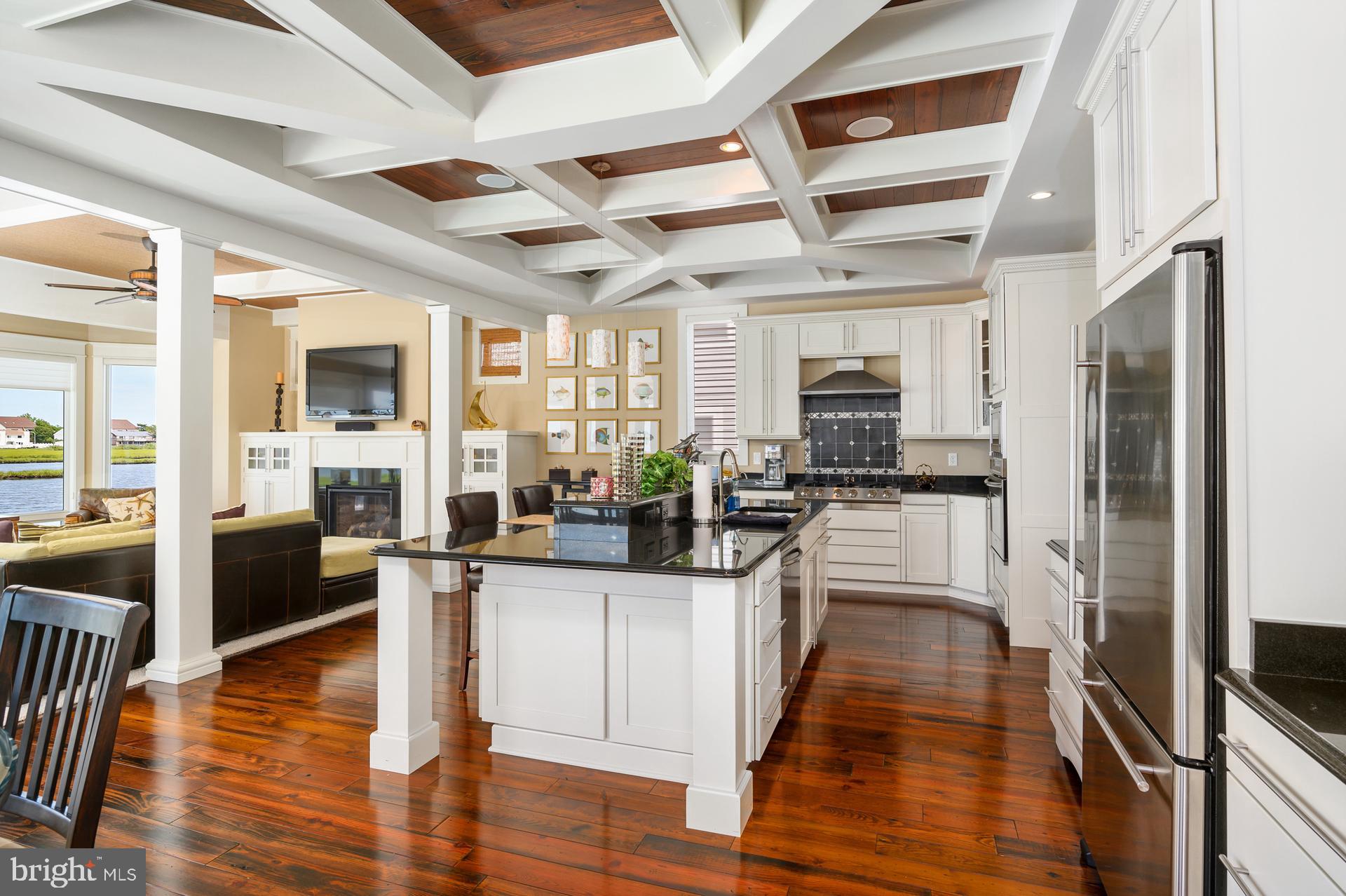 160 Channel Buoy Road Ocean City, MD 21842 - Photo 9 of 71 a kitchen with stainless steel appliances kitchen island granite countertop a stove and cabinets with wooden floor
