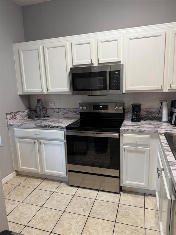 1090 Park Ridge Circle Kissimmee, FL 34746 - Photo 4 of 30 a kitchen with granite countertop a stove top oven microwave and cabinets