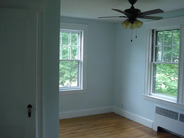 a view of an empty room with a window and wooden floor