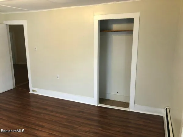 a view of an empty room with wooden floor and closet