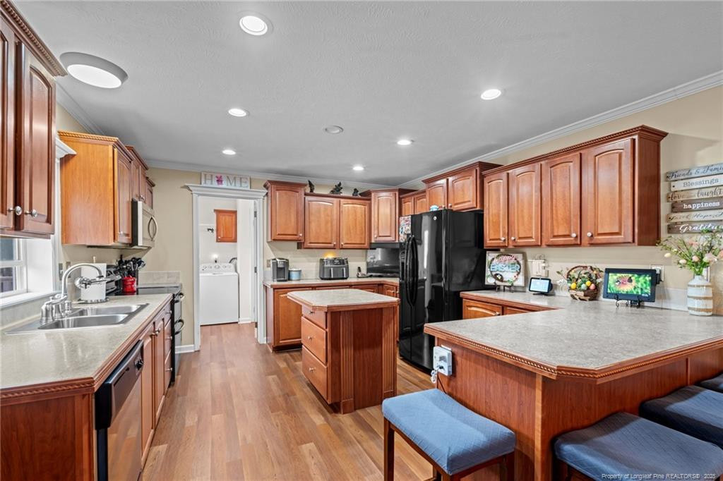 4194 Abattoir Road Angier, NC 27501 - Photo 14 of 50 a kitchen with a refrigerator a stove top oven a sink dishwasher and wooden cabinets with wooden floor