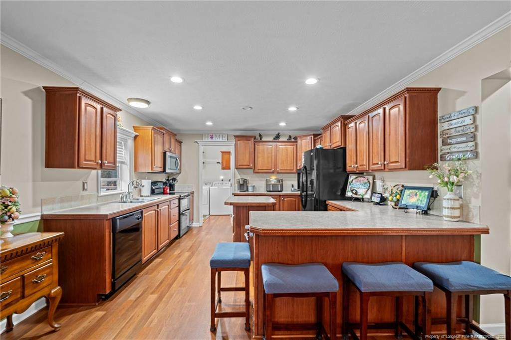 4194 Abattoir Road Angier, NC 27501 - Photo 15 of 50 a kitchen with stainless steel appliances granite countertop a stove top oven a sink dishwasher a dining table and chairs with wooden floor