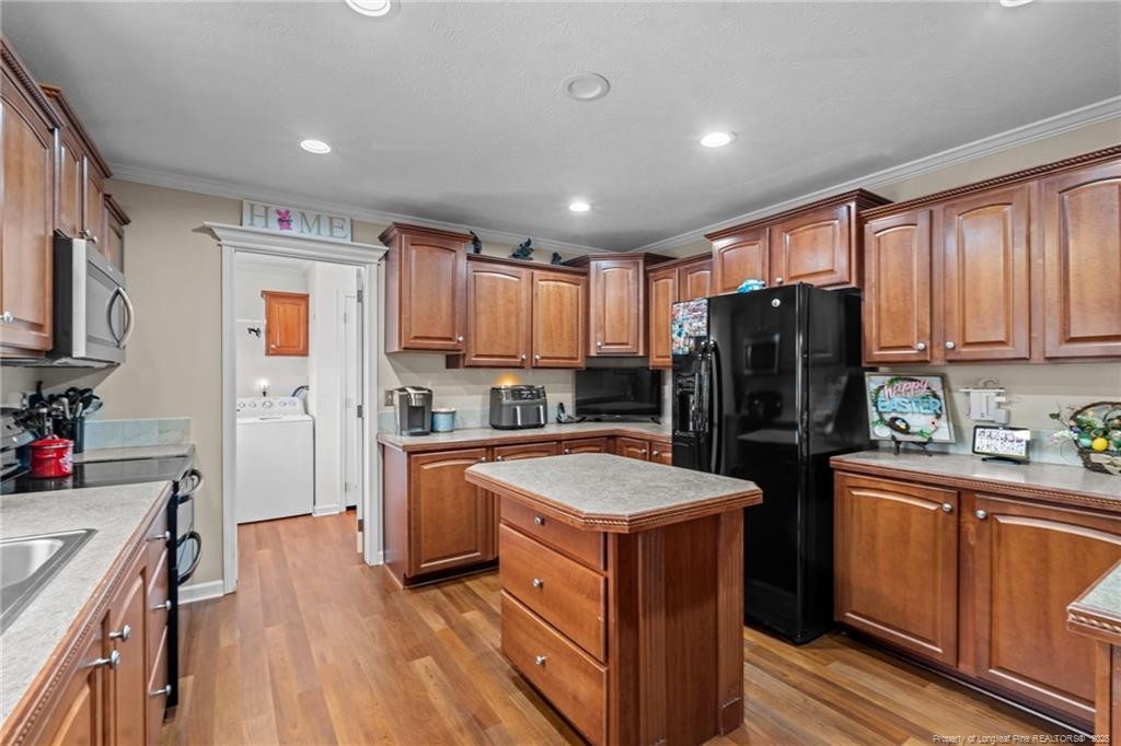 4194 Abattoir Road Angier, NC 27501 - Photo 16 of 50 a kitchen with a refrigerator a stove top oven a sink dishwasher and wooden cabinets with wooden floor