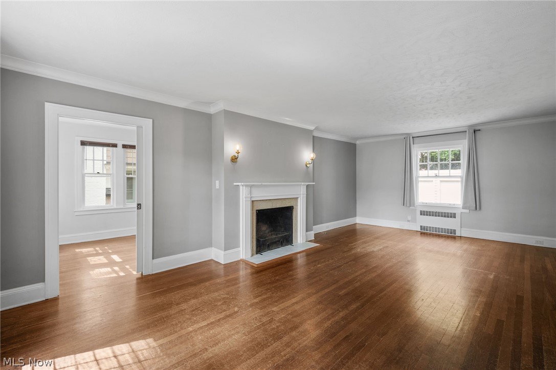 2924 Brighton Road Shaker Heights, OH 44120 - Photo 13 of 31 Unfurnished living room featuring radiator, a fireplace with flush hearth, wood finished floors, baseboards, and ornamental molding
