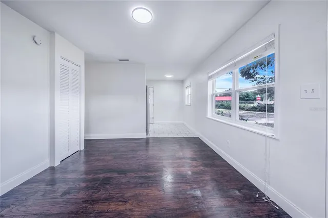 a view of an empty room with wooden floor and a window