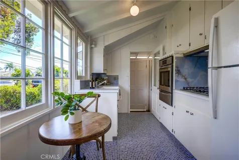 a kitchen with stainless steel appliances granite countertop a refrigerator a sink a stove and white cabinets with wooden floor